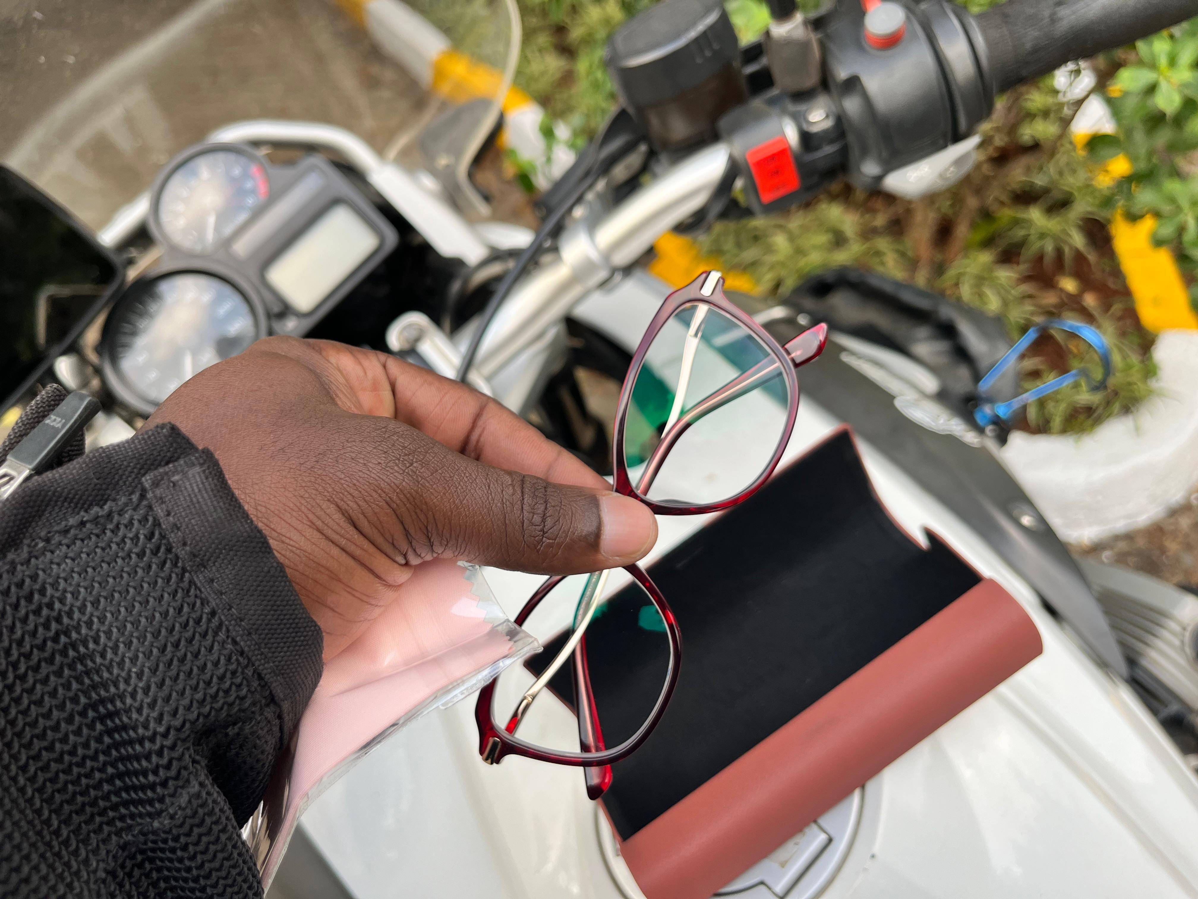 Hand holding eyeglasses near motorcycle